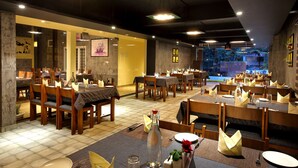 A restaurant with multiple dining tables and chairs, arranged in a spacious layout. - Wood Note Thekkady (Peermade)