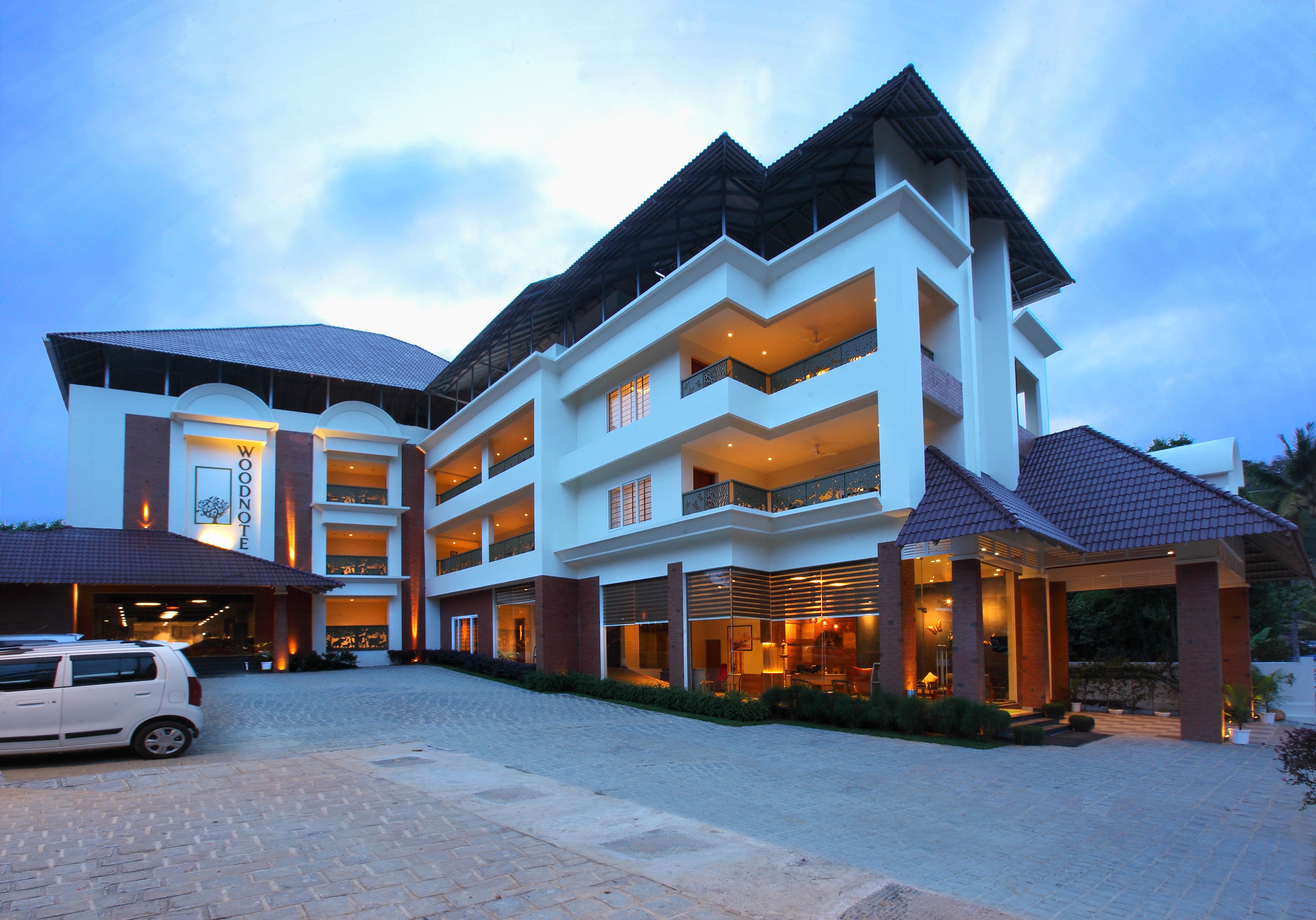 Ein mehrstöckiges Hotel mit modernem architektonischen Design, mit Balkonen und einem überdachten Eingangsbereich.