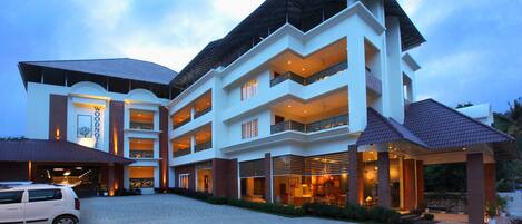 A multi-story hotel with a modern architectural design, featuring balconies and a covered entrance area.