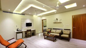 A modern living room with a sofa set, a rocking chair, a coffee table, and a TV mounted on the wall. - Wood Note Thekkady (Peermade)