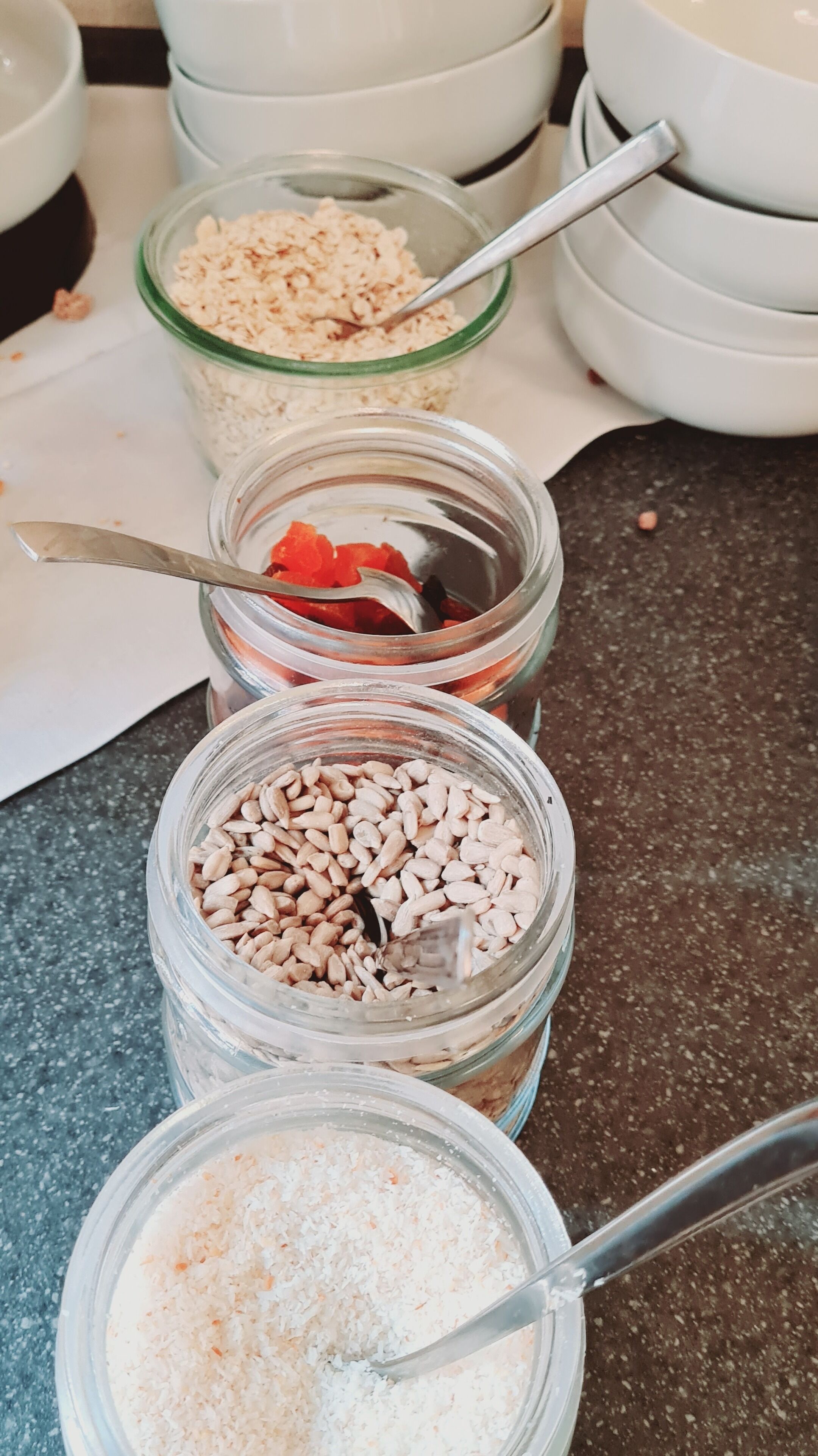 Drie glazen potten met verschillende soorten eten op een aanrecht.