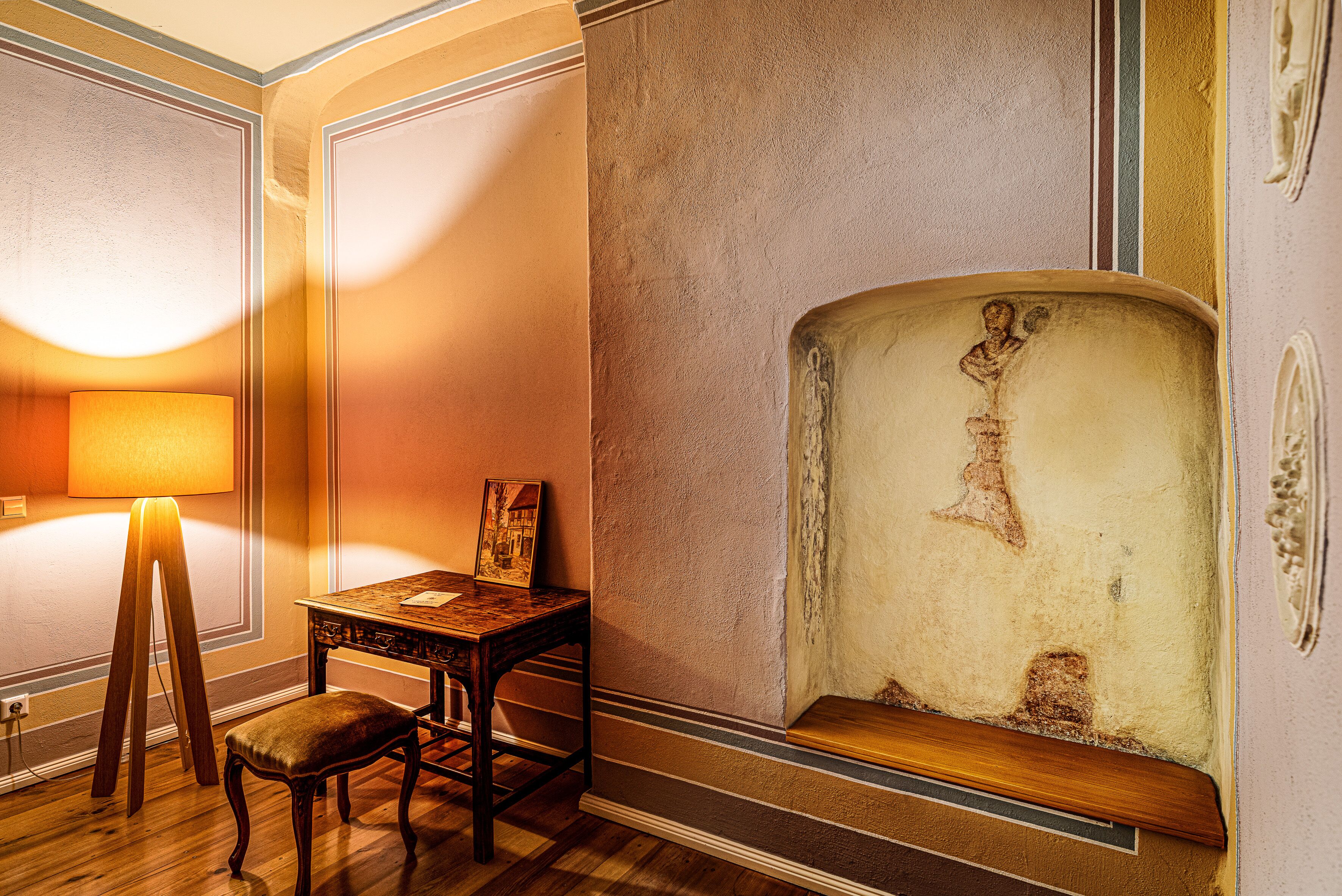 A room with a wooden table, a bench, and a lamp.