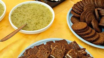 A tray of oysters garnished with lemon slices, a bowl of green soup, and a plate of brownies.