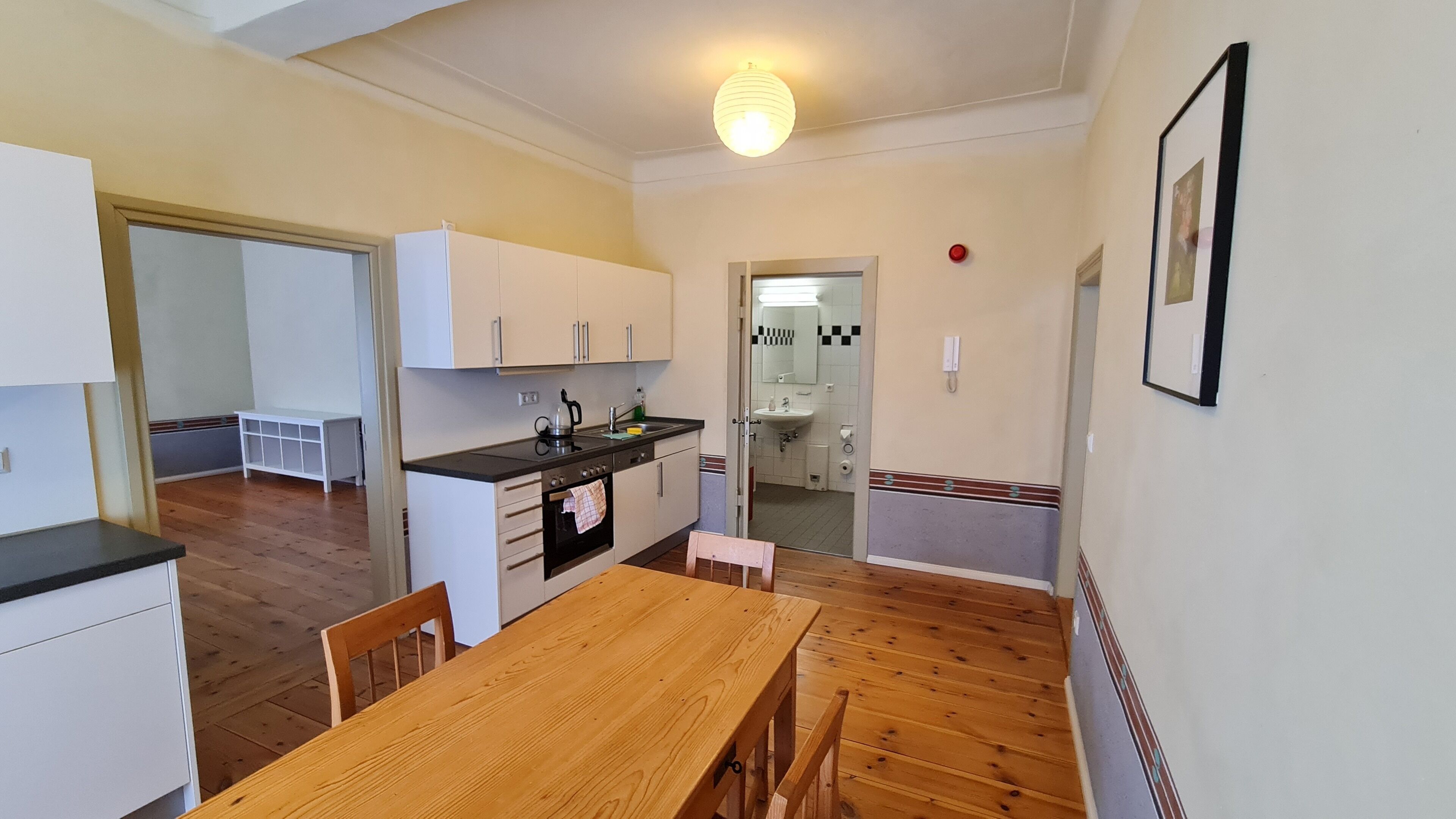 Une cuisine compacte comprenant une table et des chaises, un petit évier et une cuisinière.