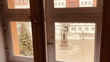 Una ventana con vistas a un patio que presenta una estatua y un edificio con techo rojo.