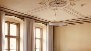 Ein Hotelzimmer mit einem großen Bett, einem runden Tisch und zwei mit Vorhängen versehenen Fenstern.