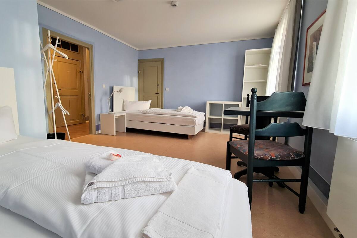 Een hotelkamer met een bed, een bureau, een stoel en een kledingkast.