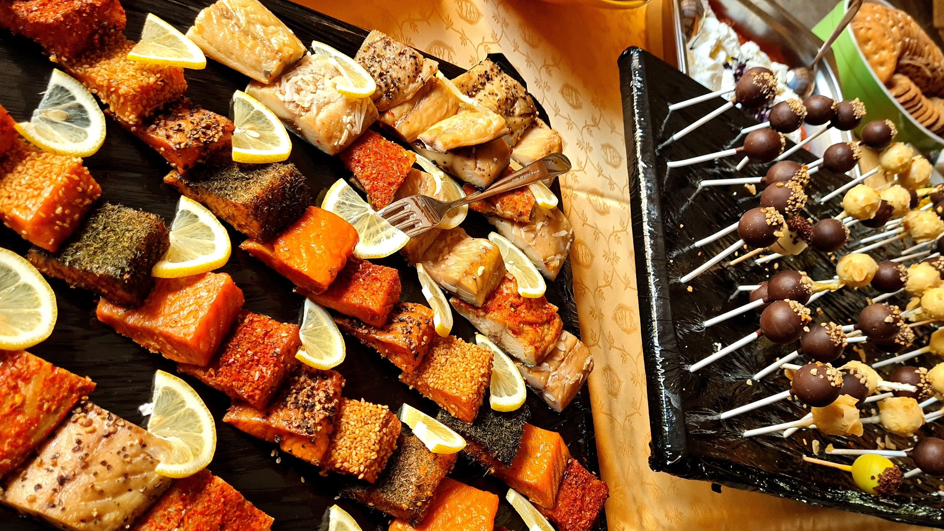 Variedad de carnes y verduras a la parrilla en una bandeja, con rodajas de limón y un tenedor.