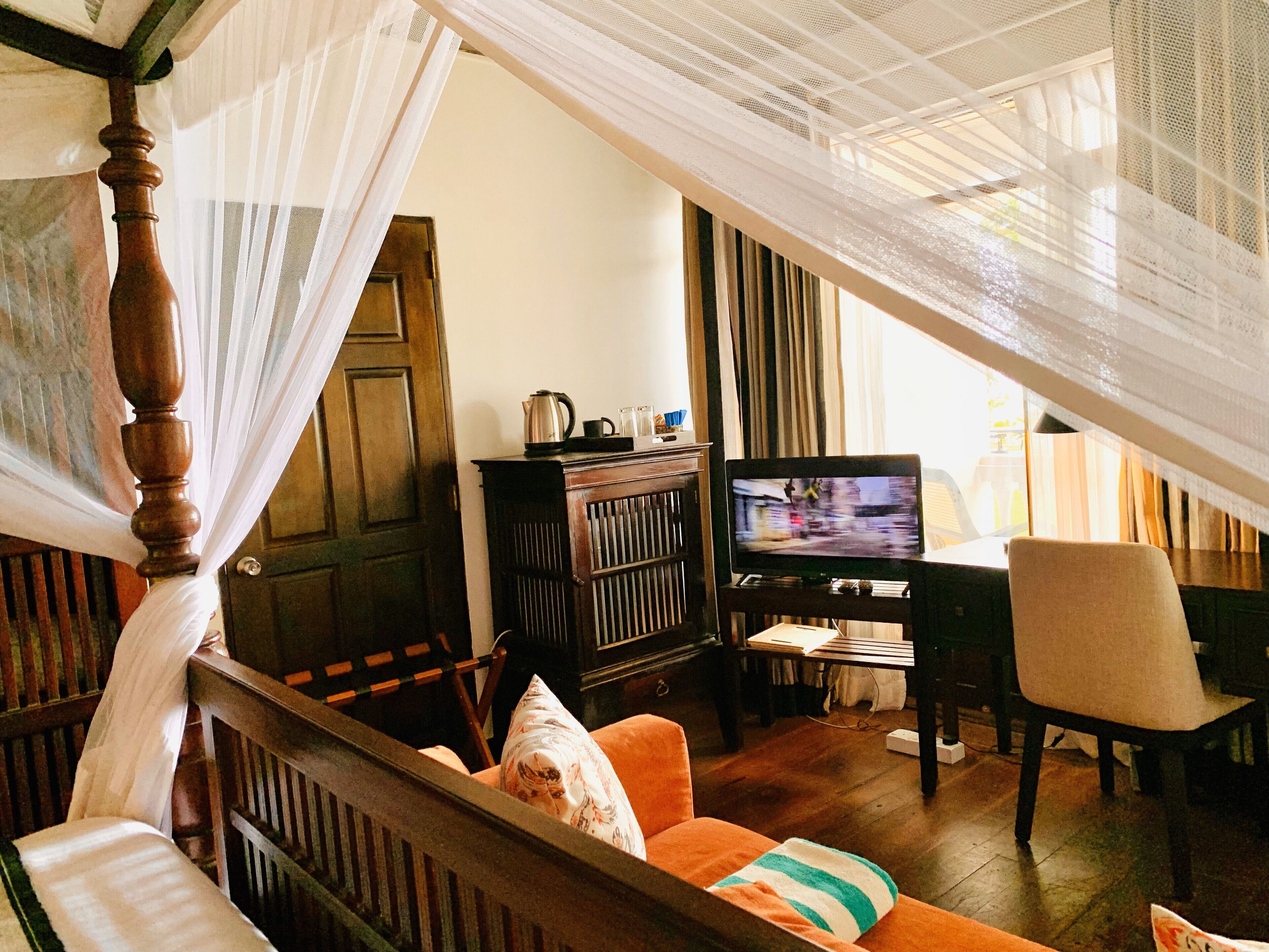 A room with a wooden bed, a television, a wooden cabinet, and a chair.