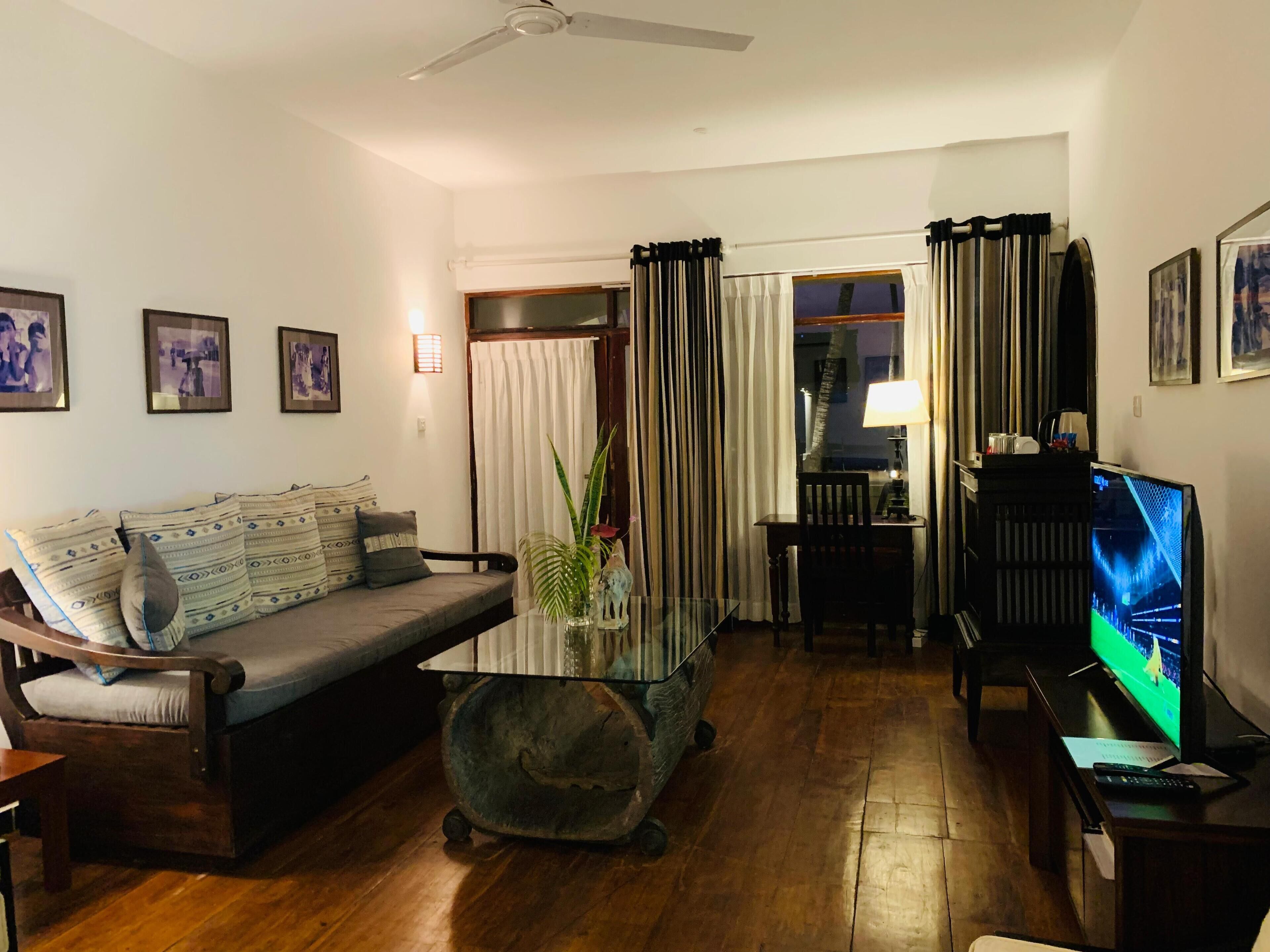 A living room with a sofa, a coffee table, a TV, and a ceiling fan.