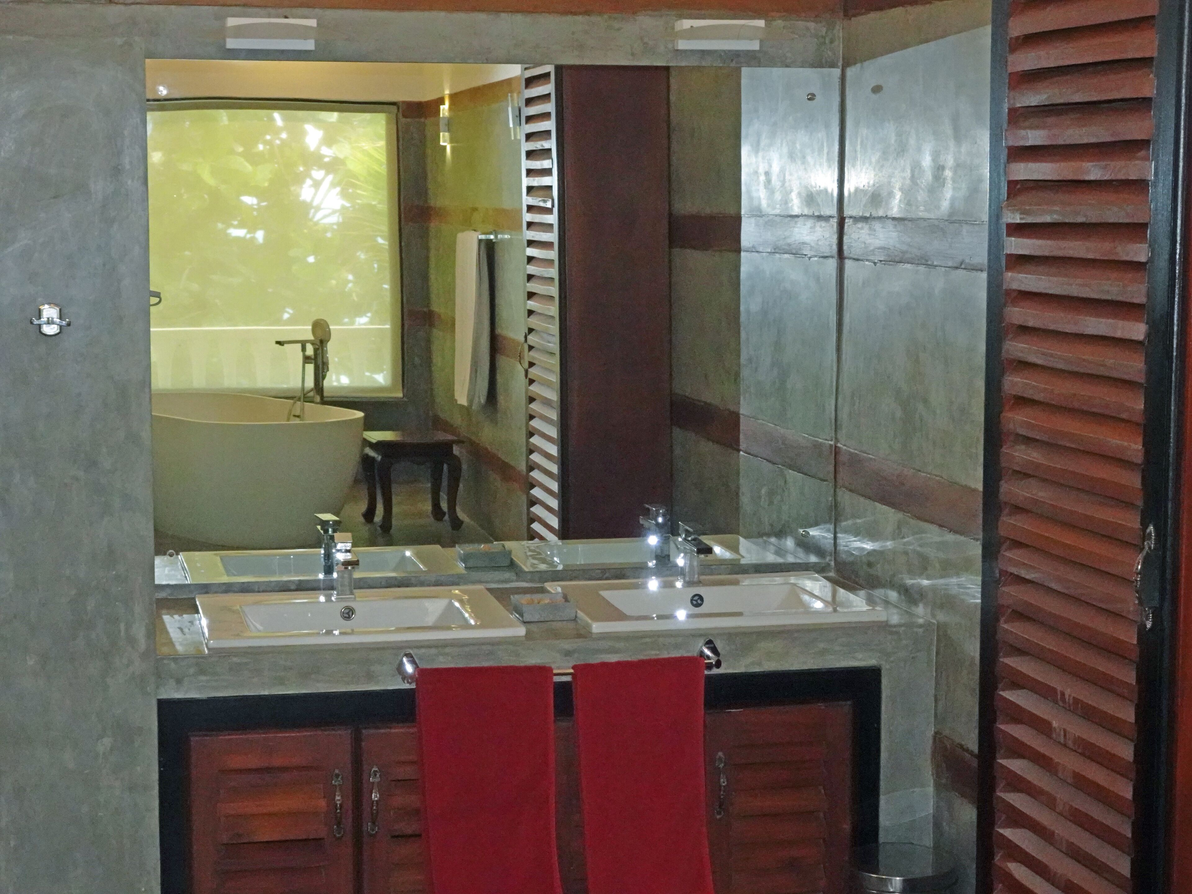 A bathroom with a large mirror, two sinks, and wooden cabinets.