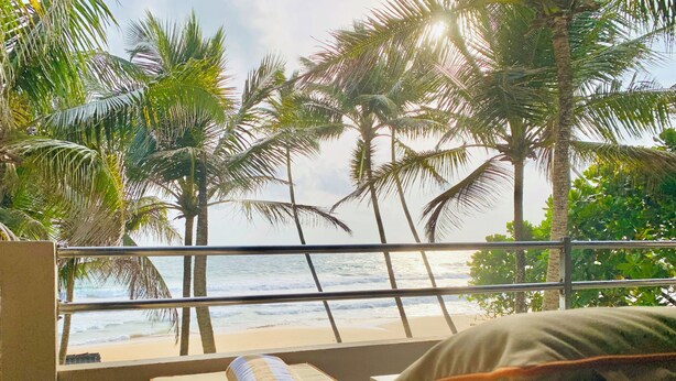 A balcony with a view of the beach and palm trees. - Suite Lanka (Hikkaduwa)