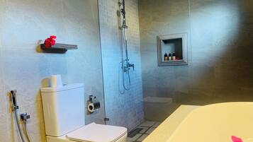 Een badkamer met een toilet, douche en bad.