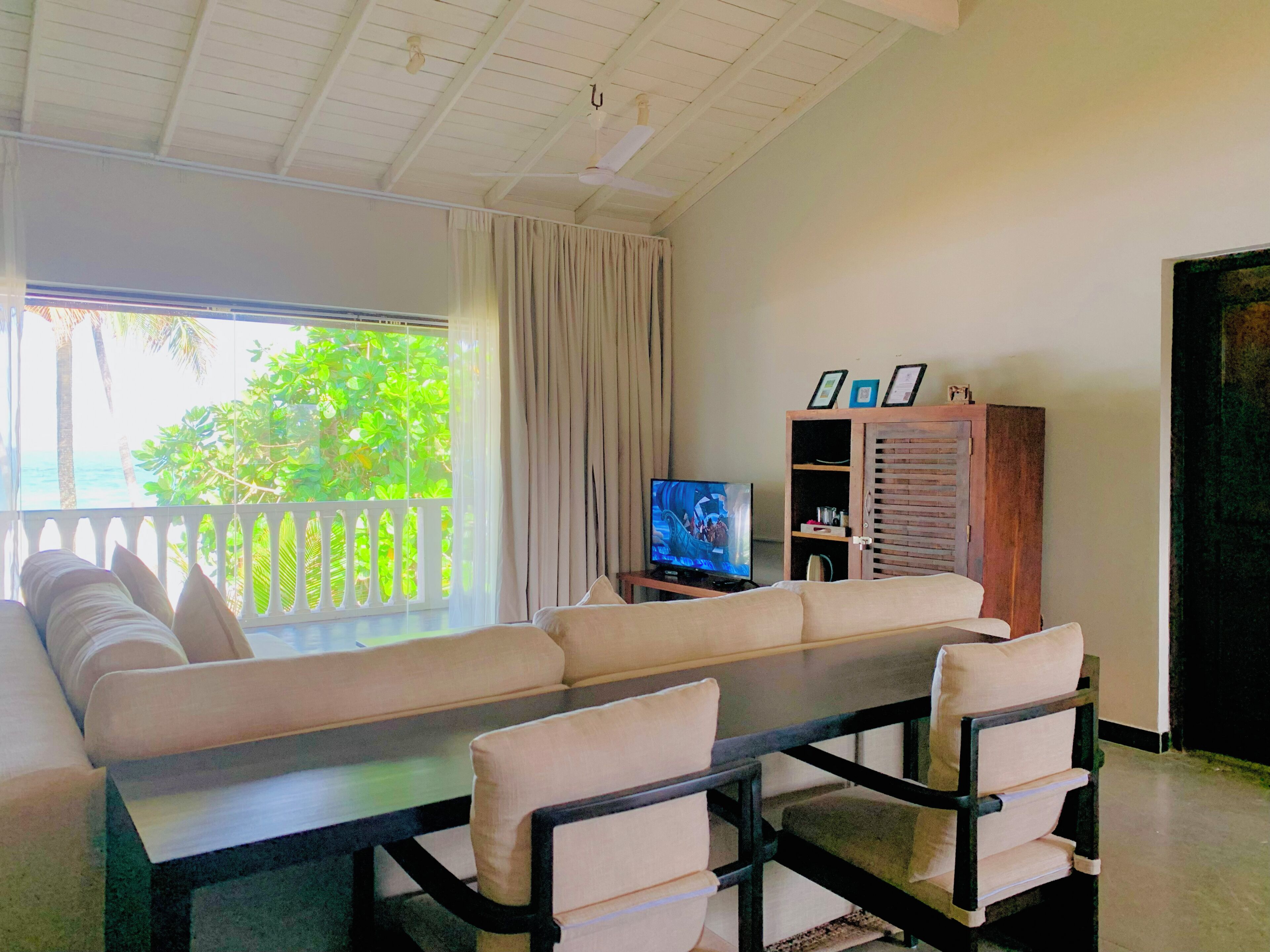Una habitación con sofá, sillas, televisión y un mueble con objetos enmarcados.