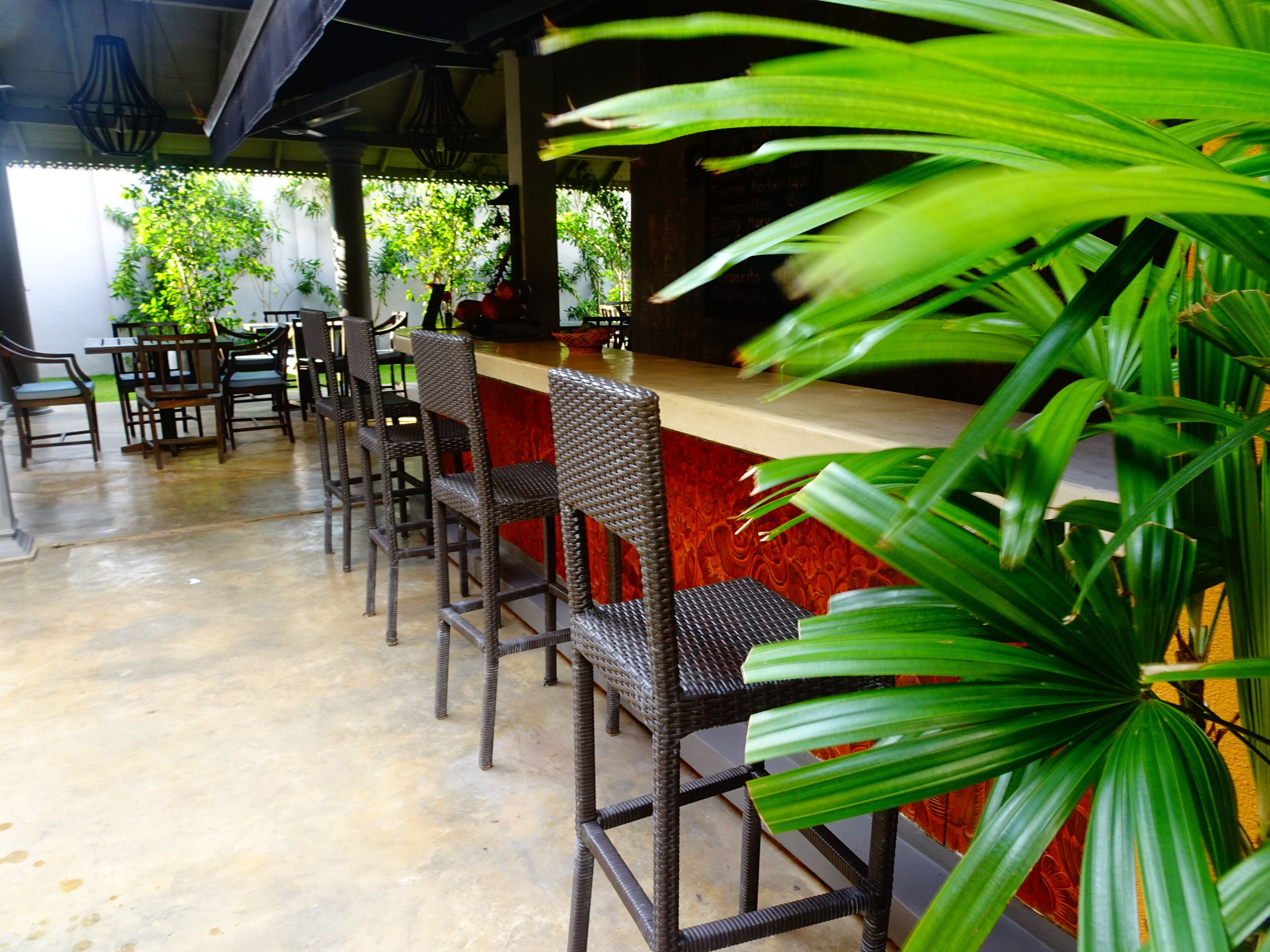 A bar area with wicker chairs and a red counter.