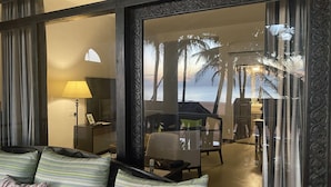 A hotel room with a view of the beach, a sofa with striped cushions, a lamp, and a table with chairs. - Suite Lanka (Hikkaduwa)