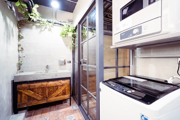 A bathroom with a wooden cabinet, a glass shower enclosure, and a white washing machine.