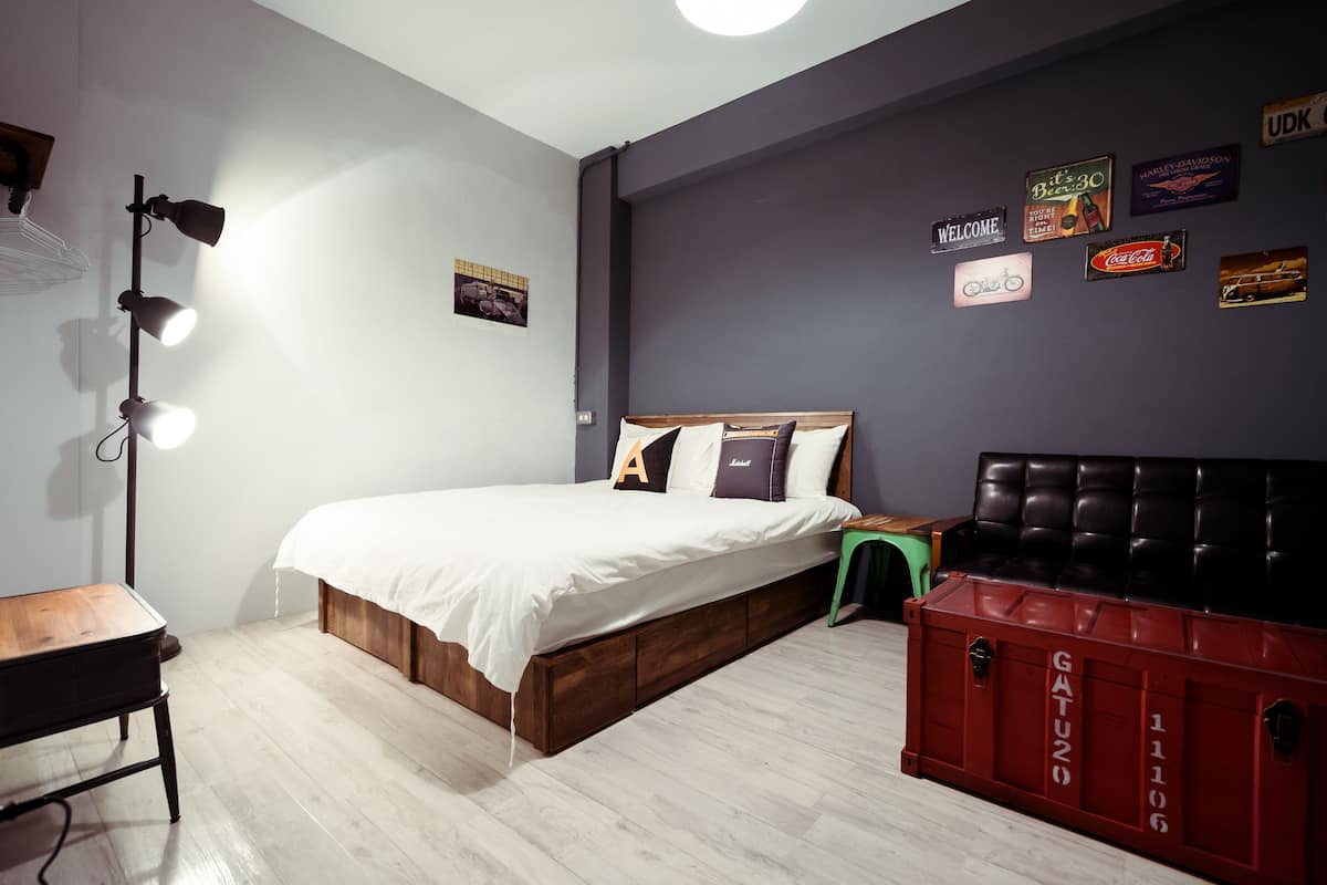 Quarto com cama, escrivaninha, luminária de chão e um móvel de armazenamento vermelho.