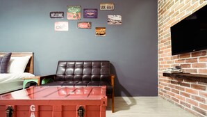 Une pièce avec un mur en briques, un canapé en cuir, un lit et un téléviseur fixé au mur.