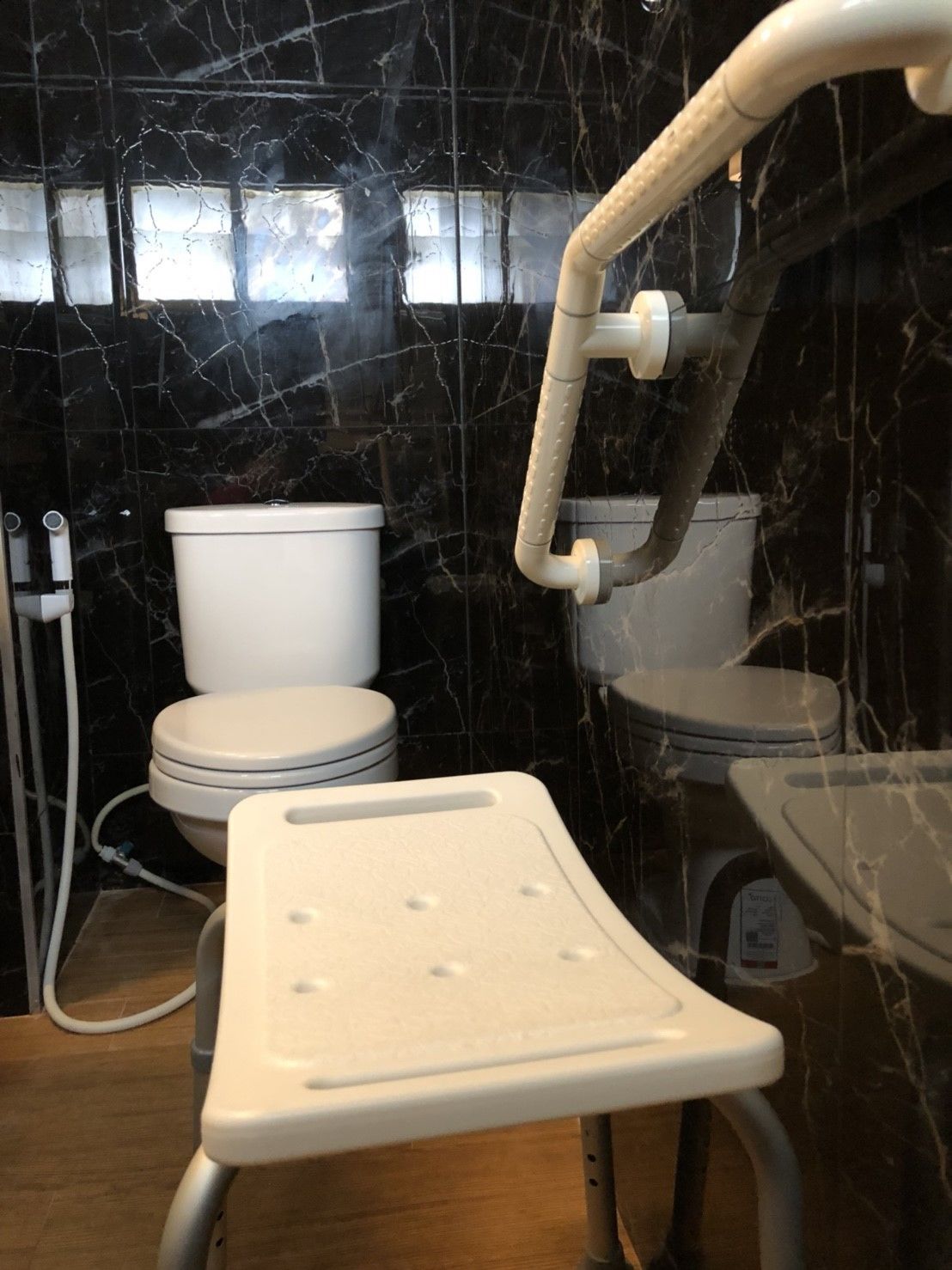 Une salle de bain équipée de toilettes, d’un bidet et d’un siège de douche.