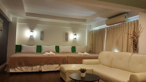 Une chambre d’hôtel avec deux lits, un canapé, une petite table et un appareil de climatisation.