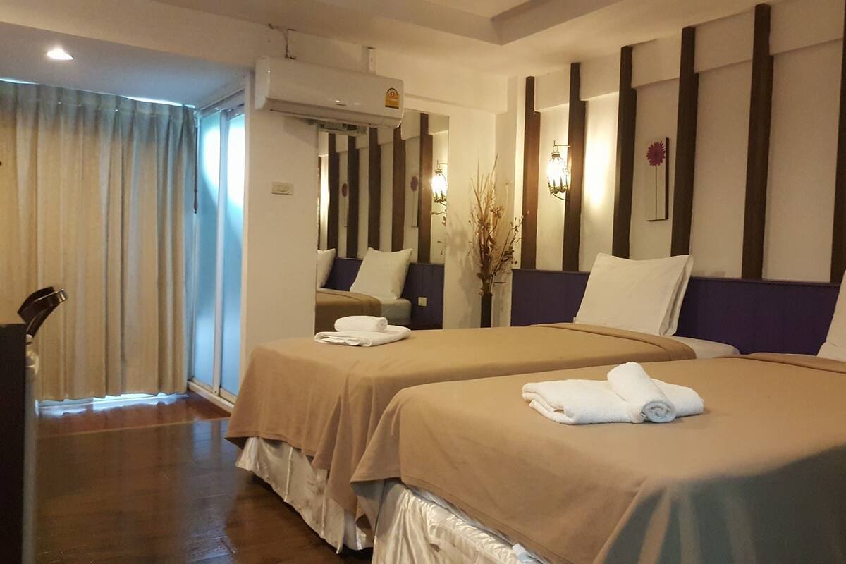 A hotel room with two beds, a bathroom, and a view of the outside.
