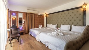 Une chambre d’hôtel avec deux lits, un bureau, une chaise et une salle de bain équipée d’un miroir et d’un porte-serviettes.