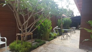 Un espace patio aménagé avec une table et des chaises, entouré de verdure et agrémenté d’une structure en bois.
