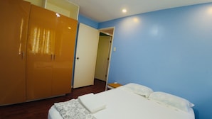 A bedroom with a bed, a wardrobe, and a door leading to another room. - Brew Home (Bacolod)