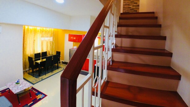 A staircase with wooden steps and white railings, leading to a dining area with a table and chairs. - Brew Home (Bacolod)