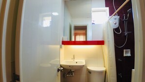A compact bathroom with a sink, toilet, and shower. - Brew Home (Bacolod)