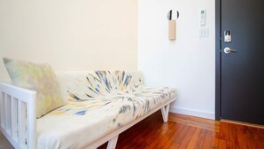 Ein weißes Sofa mit farbigem abstrakten Muster, Holzboden und eine dunkle Tür mit Schlüsselloch.