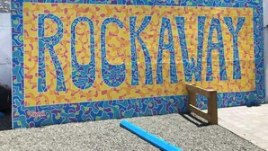 Ein farbenfrohes Straßenschild mit dem Schriftzug "ROCKAWAY" in großen Lettern.