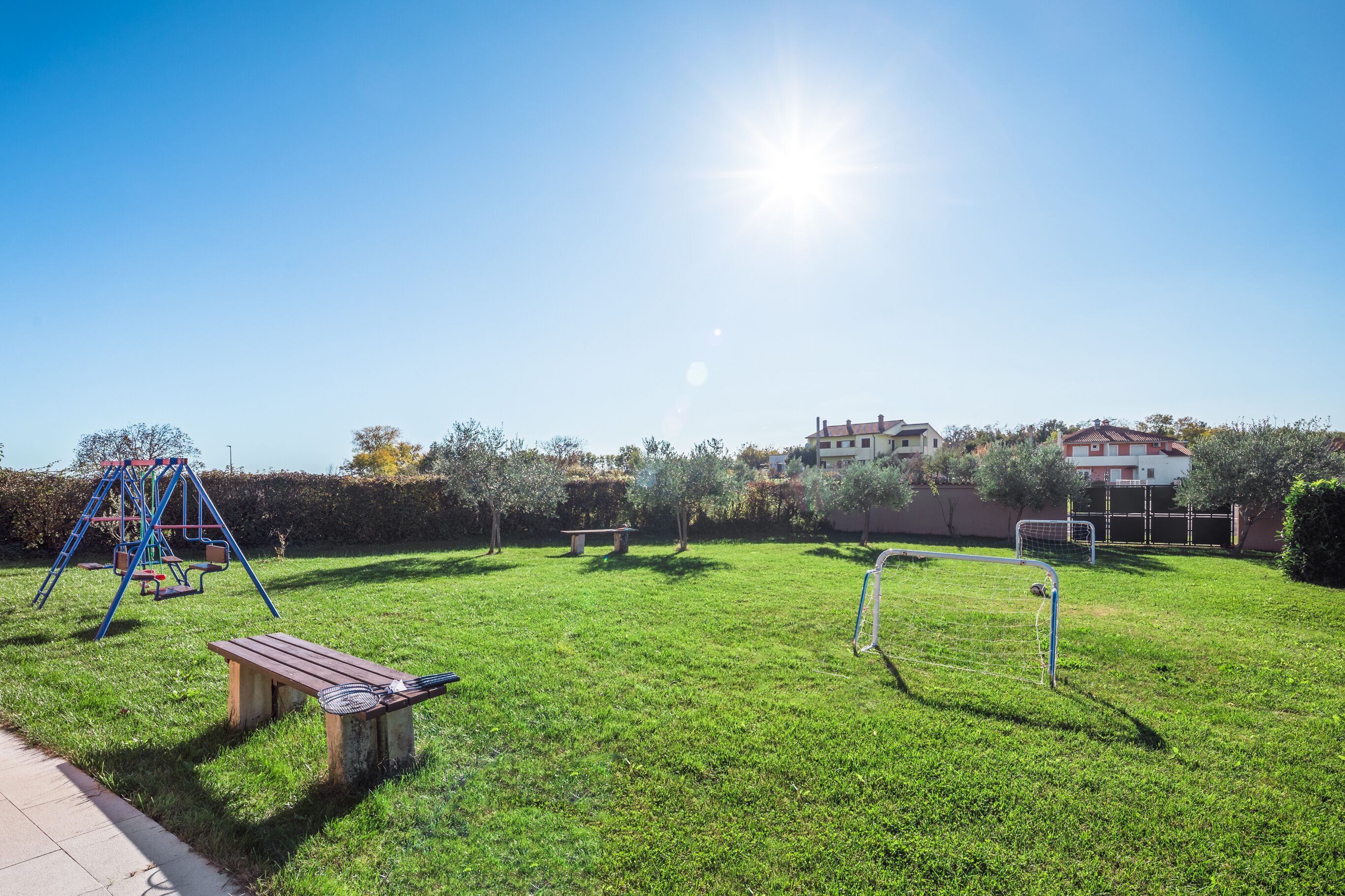 Un espace extérieur verdoyant avec une balançoire, un banc et un but de football.