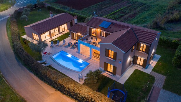 A modern two-story house with a swimming pool, outdoor seating, and a well-maintained garden.