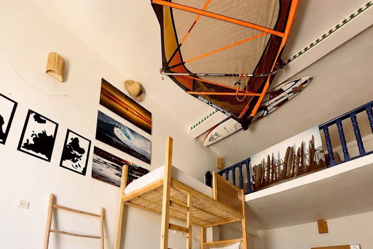 A room with bunk beds, a ladder, a hammock, and a ceiling hammock.