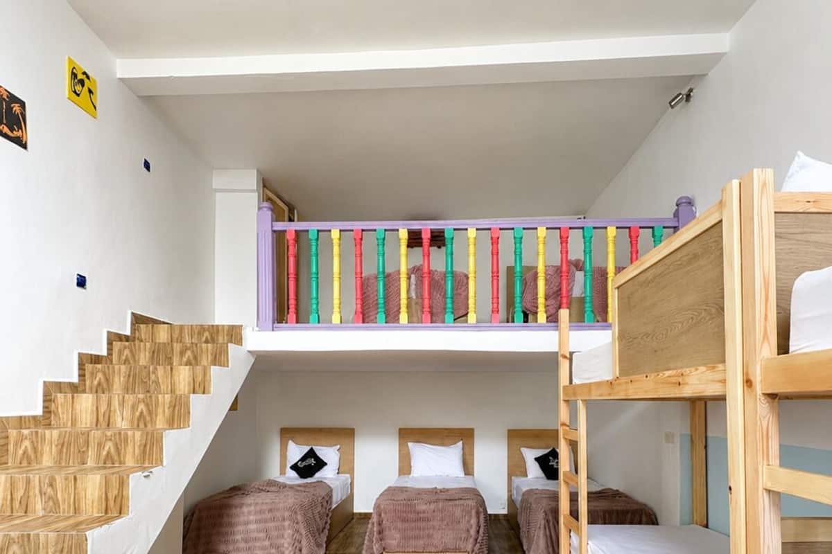 A dormitory room with bunk beds, a staircase, and a small upper sleeping area.