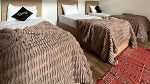 A room with three beds, each with a wooden headboard and white bedding. - Yousurf Surf House (Essaouira)