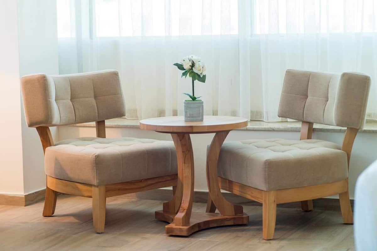 Een kamer met twee comfortabele stoelen en een houten tafel met een bloevas.