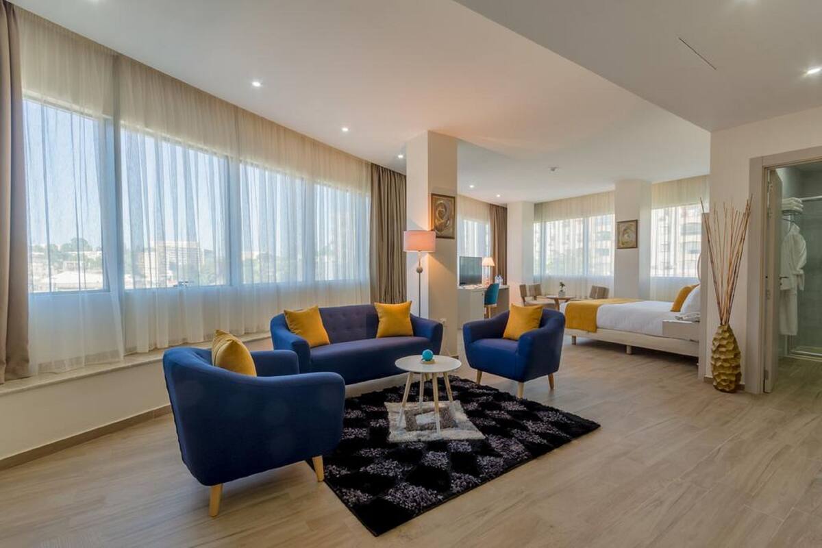 Een moderne hotelkamer met een groot raam, een zithoek, een bed en een kleine tafel.