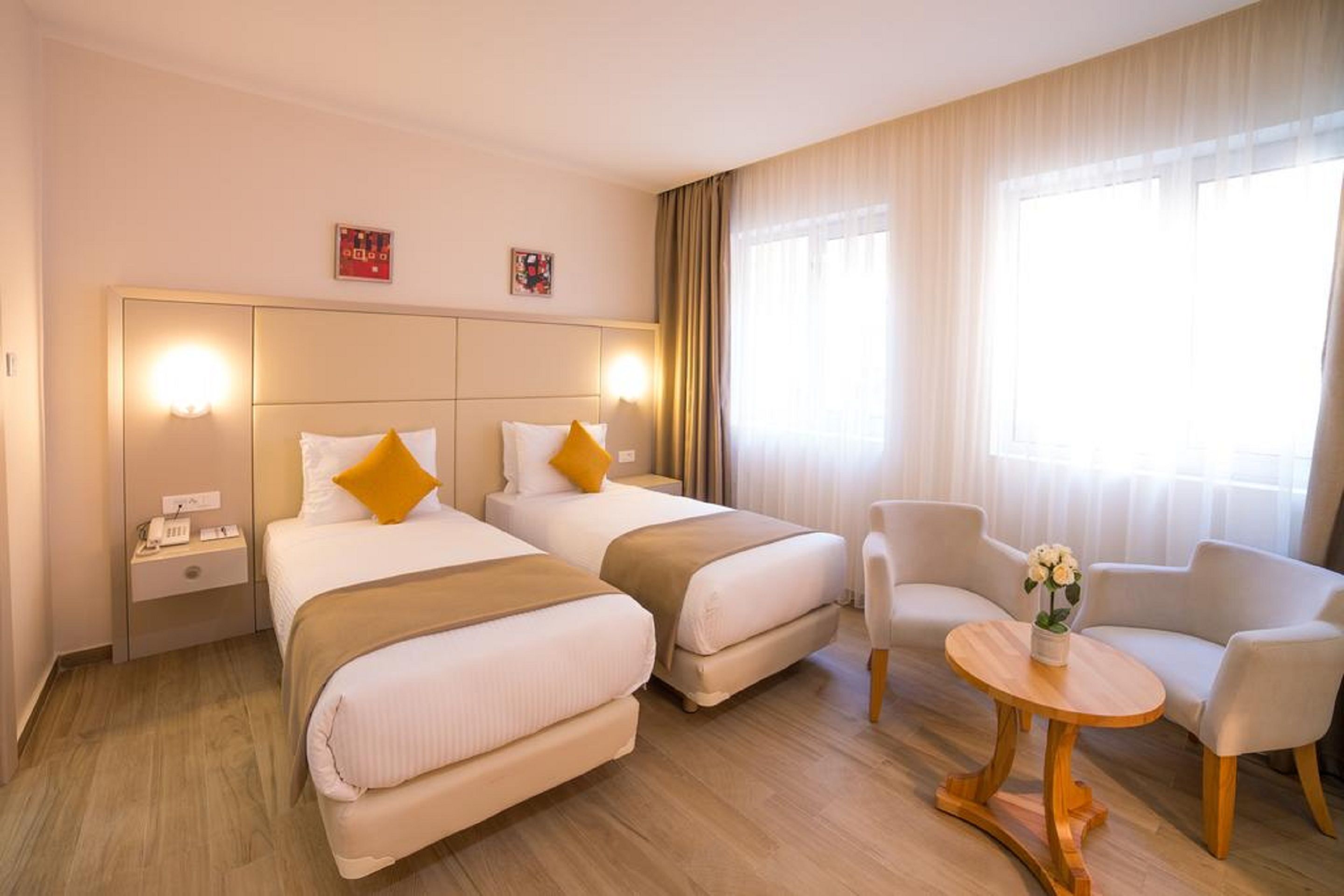 A hotel room with two beds, a small table, and a chair.