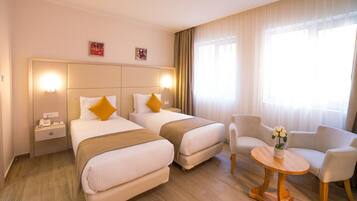A hotel room with two beds, a small table, and a chair.