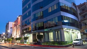 Un edificio moderno de varios pisos con fachada curva, grandes ventanales y una entrada a nivel de calle con escaleras.