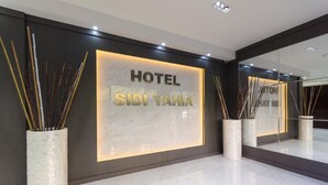 Una entrada de hotel moderna con un gran letrero iluminado que dice "HOTEL SIDI YAHA".
