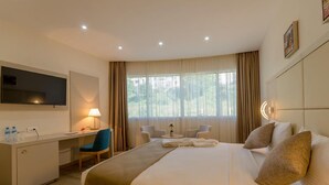 Habitación de hotel con cama, escritorio, sillas y televisor.
