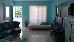 A room with a bed, a sofa, a television, and a ceiling fan. - Casa Azul Apartment (Puerto Plata)
