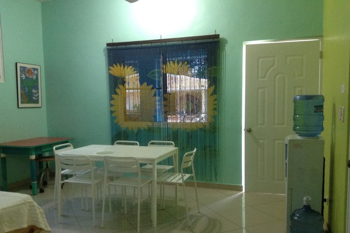A room with a dining table and chairs, a water dispenser, and a door.