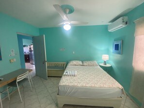 A room with a bed, a desk, a chair, a ceiling fan, and an air conditioning unit. - Casa Azul Apartment (Puerto Plata)