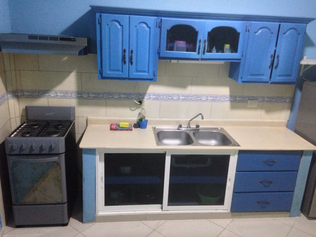 Una cocina con armarios azules, estufa, fregadero y microondas.