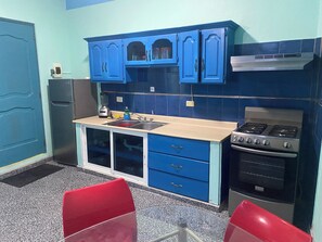 A kitchen with blue cabinets, a sink, a stove, and a refrigerator. - Casa Azul Apartment (Puerto Plata)